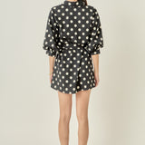 Straight-on rear view of a black and white polka dot shirt dress displaying the clean back waistline and continuous print pattern.
