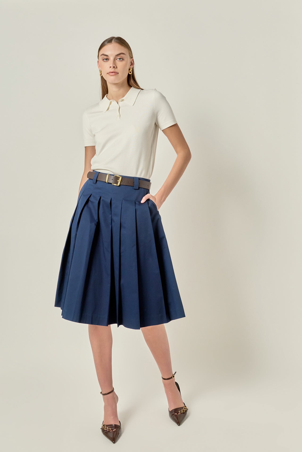 Face-forward posed view of a navy low-waist pleated midi skirt showcasing the tailored fit and A-line drape.