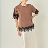 Face-forward posed view of a brown short-sleeve top with black lace trim showcasing the relaxed silhouette.