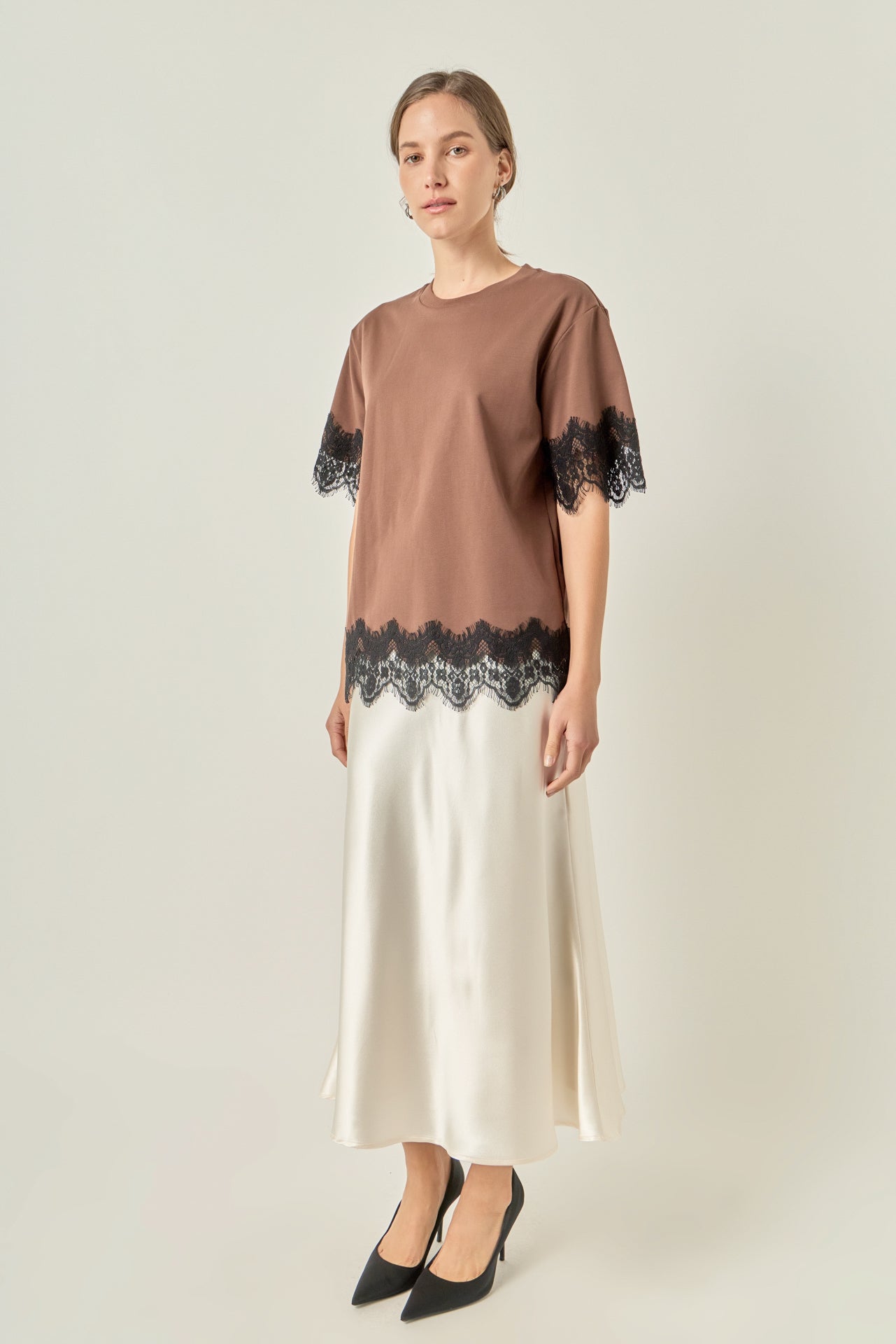 Side profile view of a brown short-sleeve top showcasing the relaxed sleeve drape and scalloped lace hem.