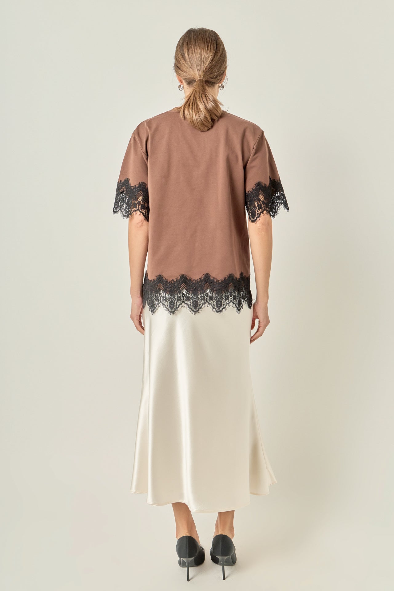 Straight-on rear view of a brown round-neck top displaying the clean back bodice and continuous lace trim along the hem.