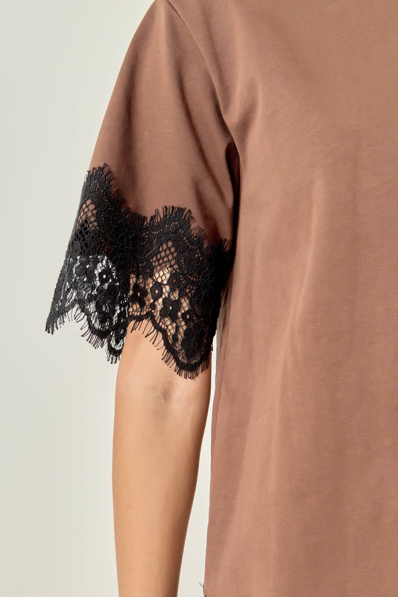 Ultra close-up detail view of brown cotton fabric paired with intricate black eyelash lace edging.