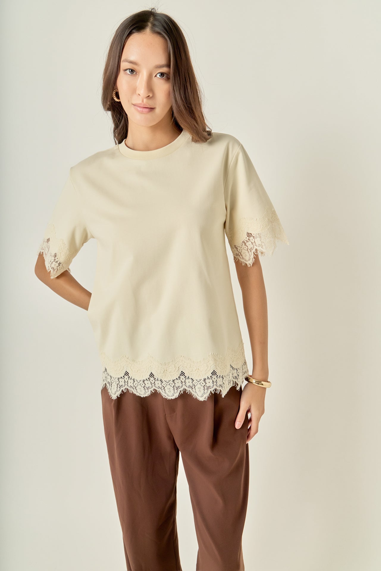 Face-forward posed view of a cream lace-trimmed short-sleeve top showcasing the effortless fit and tonal texture.