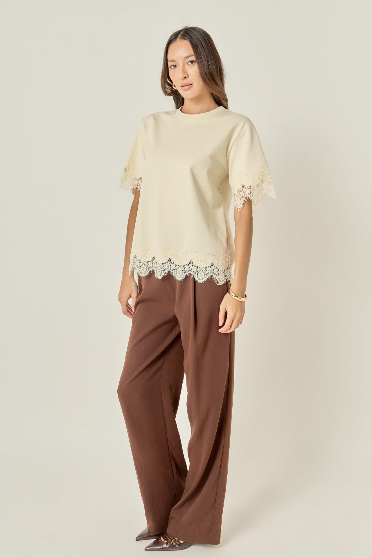 Side profile view of a cream short-sleeve top showing the straight side seam and scalloped lace cuffs.