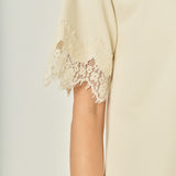 Ultra close-up detail view of cream cotton knit fabric with matching scalloped eyelash lace trim.
