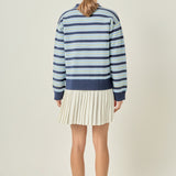 Straight-on rear view of a navy multi striped polo knit dress displaying continuous horizontal blue striping and a clean pleated back hem.