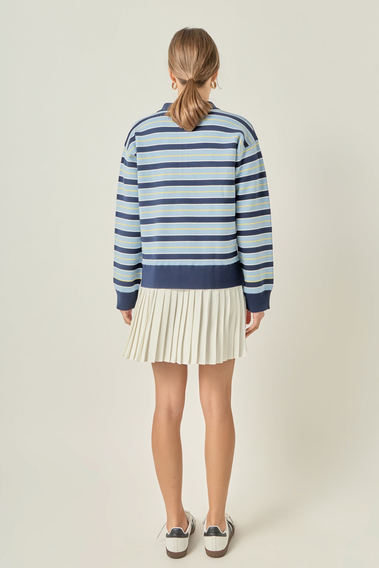 Straight-on rear view of a navy multi striped polo knit dress displaying continuous horizontal blue striping and a clean pleated back hem.
