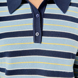 Ultra close-up detail view of blue striped knit sweater fabric layered over crisp cream pleated skirt fabric.