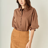 Three-quarter posed view of a brown pinstripe balloon sleeve shirt demonstrating the overall relaxed fit and sleeve drape.