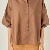 Waist-up untucked view of a brown pinstripe shirt highlighting the point collar, center-front button placket, and relaxed hemline.
