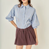 Three-quarter posed view of a dusty blue striped balloon sleeve shirt showcasing the loose fit and overall silhouette.