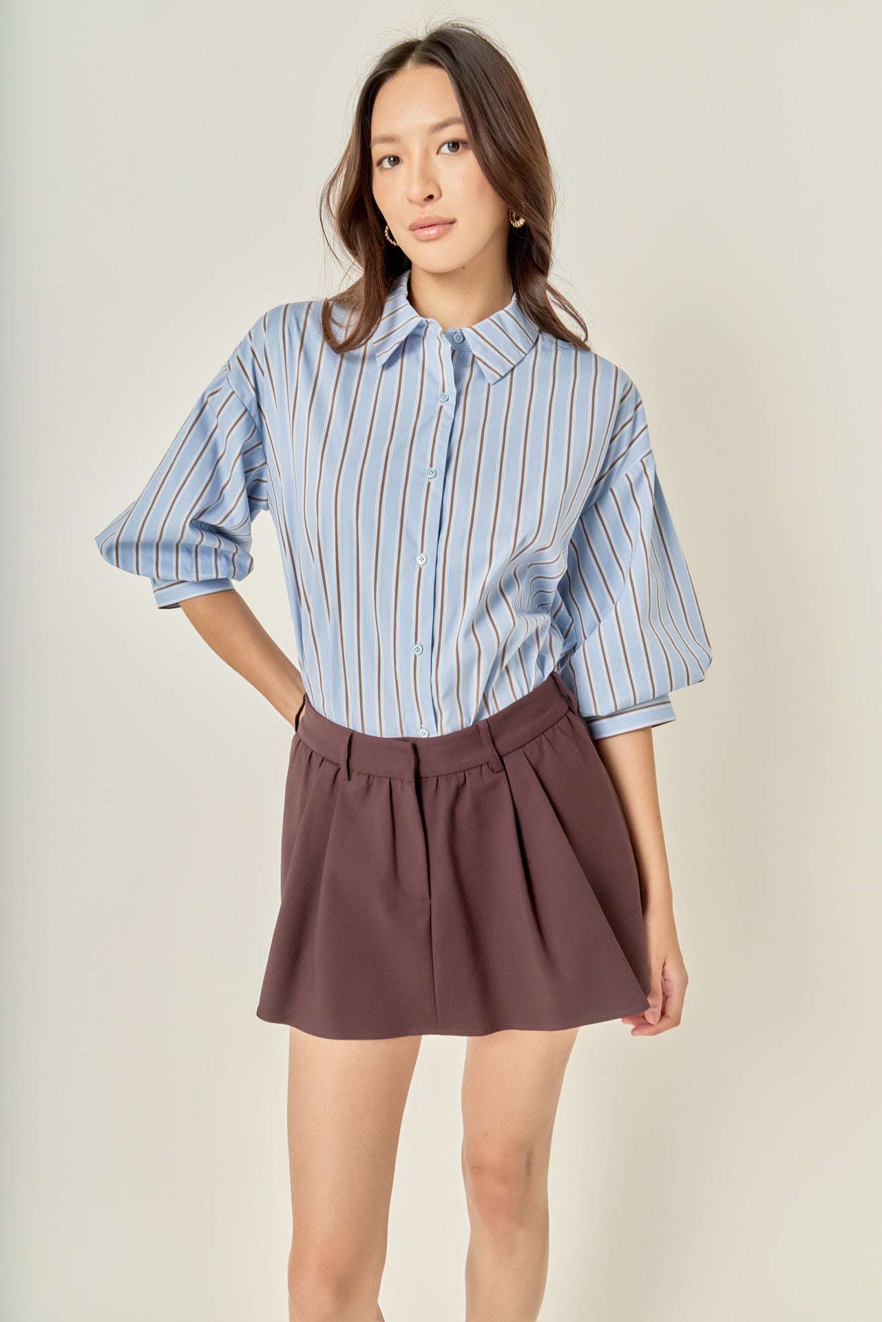 Three-quarter posed view of a dusty blue striped balloon sleeve shirt showcasing the loose fit and overall silhouette.